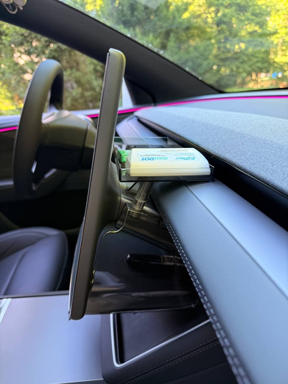 Fixed EVBASE under-screen tray holding a small item behind Tesla screen
