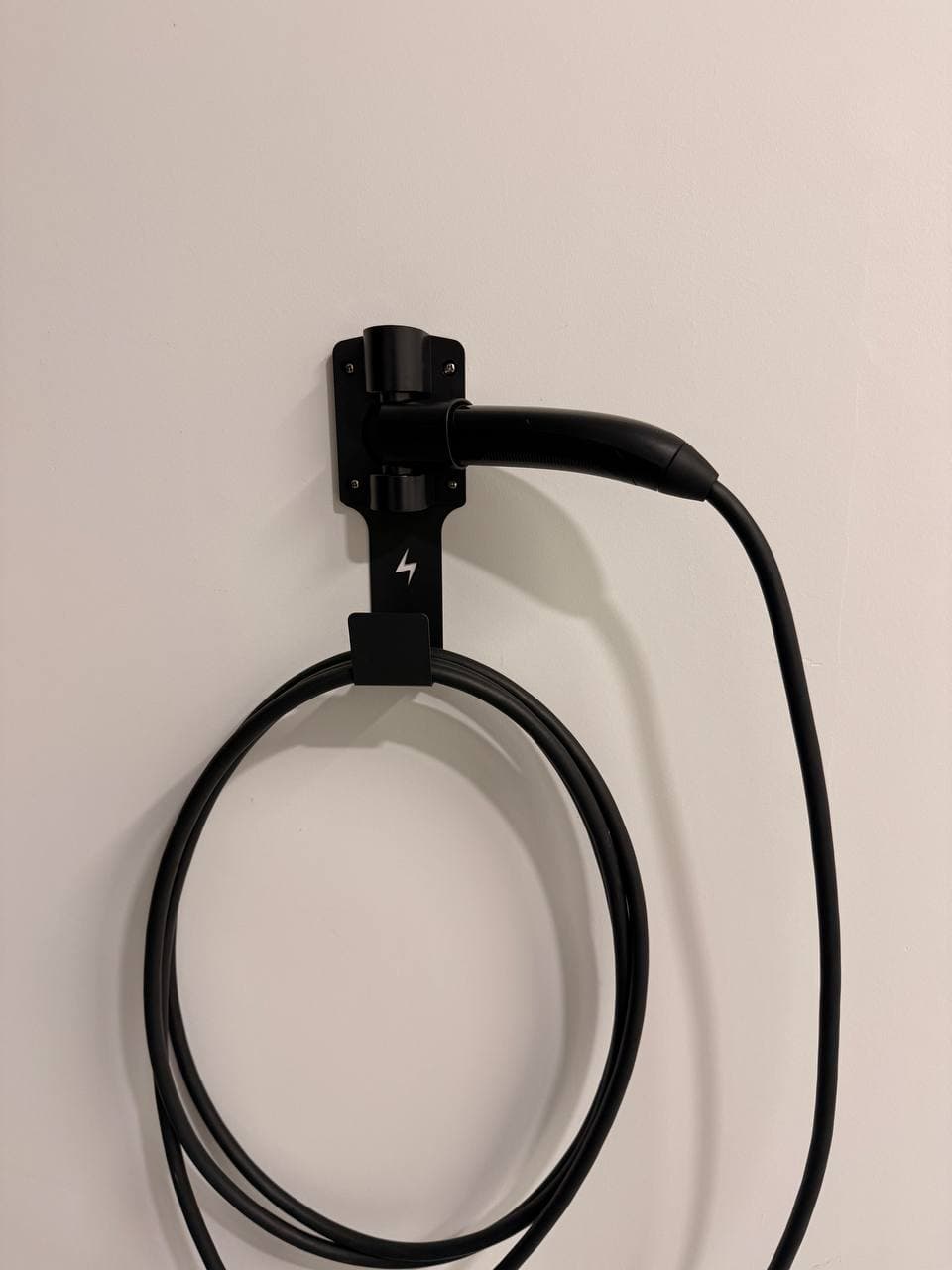 Close-up of FOCSPROD rotating Tesla charge-handle dock installed on a garage wall