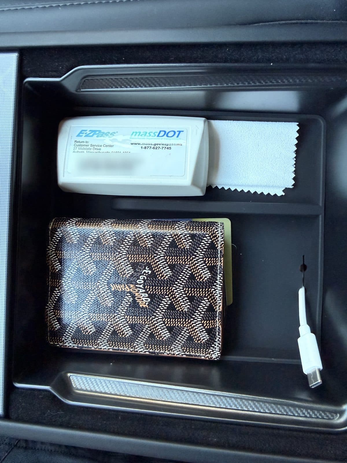 SUMK armrest tray loaded with a toll transponder, cloth and wallet, with a USB-C cable routed through the side slot