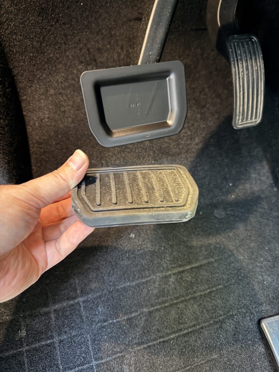 Stock Tesla Model Y Juniper rubber brake pad removed, showing the bare brake pedal plate